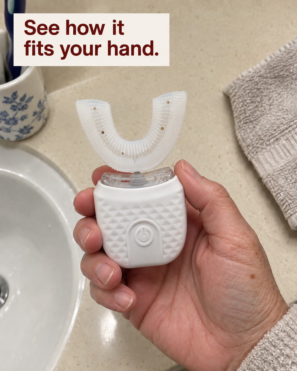 U Brush in an older adult’s hand, showing the broad handle and central button